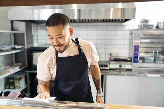 Radiant young Asian man enjoying his job as restaurant chef