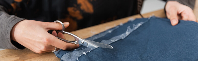 Cropped view of african american craftswoman cutting cloth in workshop, banner.
