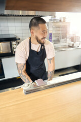 Cute young man in black apron working at the restaurant