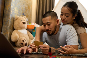 Cute asian couple sit on floor in front of laptop