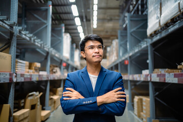Portrait of a confident Asian businessman. Standing in a large warehouse. Wholesale, logistics, business, export. The manager inspects the goods at the warehouse. Logistics and export of business.