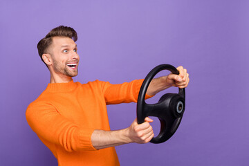 Photo of funky excited guy dressed orange pullover riding auto looking empty space isolated purple...