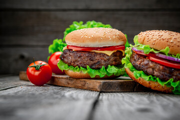 Two delicious homemade burgers of beef on an old wooden table. Fat unhealthy food close-up.
