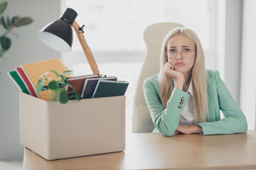Photo of unhappy upset woman dressed teal blazer collecting belongings leaving work forever indoors...