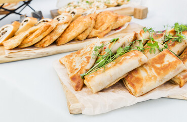 Pancakes stuffed with ham and cheese, chicken and vegetables on a banquet table