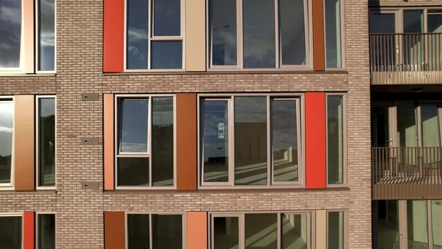Closeup and aerial reveal of exterior facade of newly build apartment complex showing wider skyline of Hanseatic tower town of Zutphen.