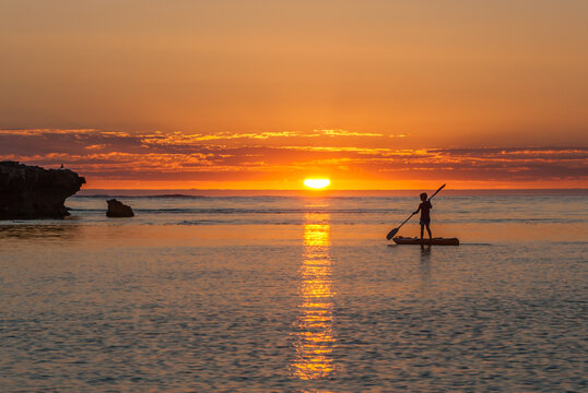 Boy Standing on Canoe at Sunset