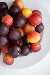 yellow and purple plums on a white plate. Isolate, healthy fruit dessert, cherry plum. Delicious snack, seasonal harvest. Fruits on white, fruit plate of plums