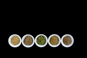 dried  herbs for Mediterranean cooking in white bowls on a black background