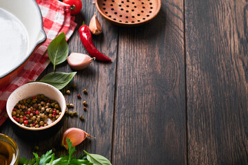 Frying pan white, black empty plate, basil leaves and spices on old wooden background. Abstract food background. Top view of dark rustic kitchen table with wooden cooking utensils, frame. Mock up.