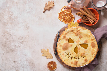 Halloween food. Homemade pumpkin pie or tart with a scary face for Halloween on a wooden table. Copy space. Halloween food concept.