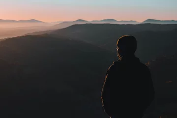 Man from behind standing and looking away at the mountains landscape in morning © Yurii Kushniruk