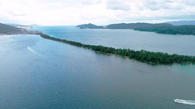 ドローンで空撮された、京都府宮津市の日本三景「天橋立」。青い海を隔てる美しい砂州と、それを取り囲む豊かな自然、歴史ある街並みを一望できる一景。観光PR、旅行広告、地域紹介など、京都の魅力を伝える映像・写真素材に。 | Drone aerial view of Amanohashidate in Miyazu, Kyoto.