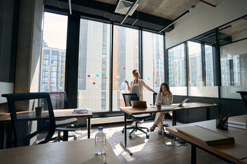 Pretty female colleagues are chatting while being in spacious office
