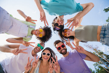 Low angle view portrait of group funny excited fellows demonstrate v-sign have good mood pastime...