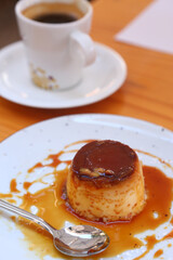  spanish flun pudding dessert closeup photo with teaspoon and cup of coffee on the background
