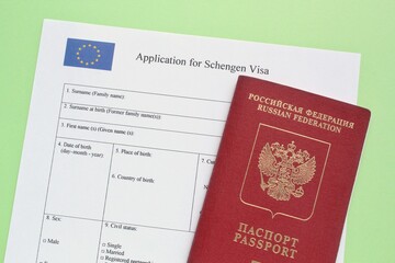 Passport of Russian Federation and application form for Schengen visa on green background. Prohibition and suspension of visas for tourists to travel to Europe, European Union, Baltic States concept