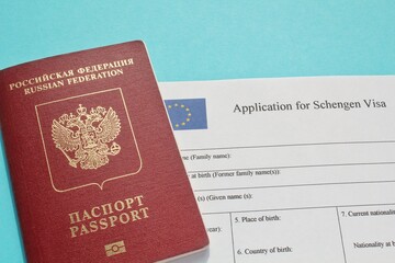 Passport of Russian Federation and application form for Schengen visa on blue background. Prohibition and suspension of visas for tourists to travel to Europe, European Union and Baltic States concept