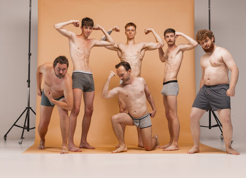 Young cheerful people, men of different body types standing together in underwear at studio photo shoot. Concept of body positive, fashion, friendship