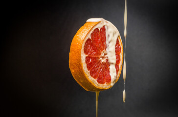 Fresh grapefruit with water yogurt drops. isolated dark background