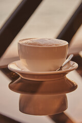A cup of cappuccino on a glass table .
