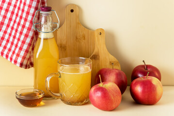 Apple Cider Vinegar in Glass Mug and Bottle with Honey and Cinnamon Red Apples Yellow Background Horizontal