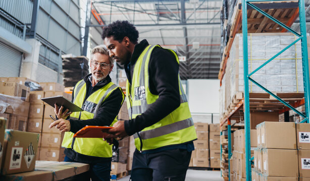 Mature warehouse manager training a new employee in order fulfilment