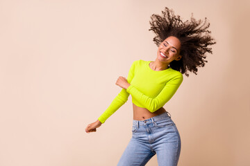 Portrait of young attractive smiling girl wear yellow top dancing good mood party isolated on beige color background
