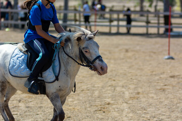 Little girl that rides a white pony during Pony Game competition at the Equestrian School