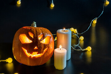 Halloween carved pumpkin. The smiling face of Jack O Lantern. Illuminated by a burning candle inside the scary Jack Lantern. Pumpkin decoration. Happy Halloween. yellow lanterns on black background