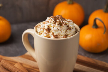 Autumn pumpkin spice latte with cream in mug on dark table close up. Traditional Coffee Drink for...