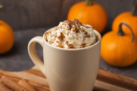 Autumn pumpkin spice latte with cream in mug on dark table close up. Traditional Coffee Drink for Autumn Holidays. Thanksgiving day or Halloween holiday. Fall time.