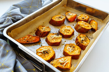 Baked sweet potato on baking sheet with herbs. Vegetarian food, dinner or lunch. soft focus