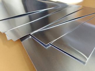 square aluminum on yellow cardboard. pile of thin metal industrial materials. set of square pieces