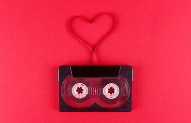Audio cassette with a film heart on a pink background. Valentine's Day