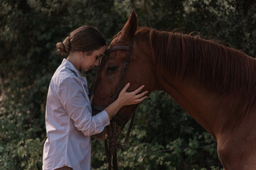 young rider giving a beautiful hug to her brown horse 