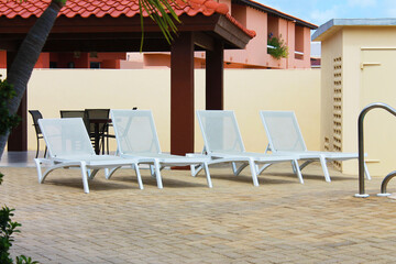 A row of white deck chairs on a pool deck, Aruba