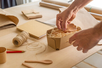 hands packing wooden spoons. table with recycled and disposable objects
