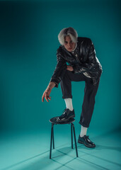 Male beauty concept. Portrait of fashionable young man with stylish haircut wearing trendy glasses and sweater, posing over gray background. Perfect hair & skin. Hipster style. Copy-space. Studio shot