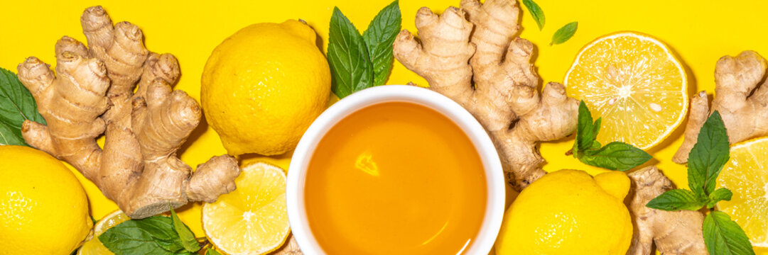 Healthy organic vegan immunity booster, herbal drink. Antioxidant anti-inflammatory ginger lemon tea with ingredient - fresh ginger, lemon, mint, bright yellow background flatlay top view copy space