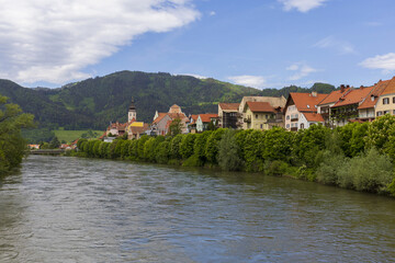Panoramic view across a river to medieval Austrian village across on summer sunny day, pastoral Alpine landscape