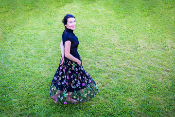 A young attractive woman in black clothes dancing in a backyard