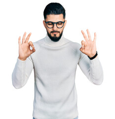 Young arab man with beard wearing elegant turtleneck sweater and glasses relaxed and smiling with eyes closed doing meditation gesture with fingers. yoga concept.