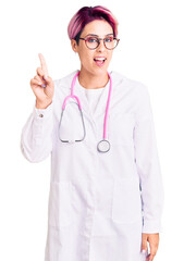 Young beautiful woman with pink hair wearing doctor uniform showing and pointing up with finger number one while smiling confident and happy.