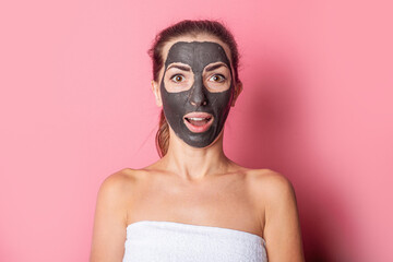 Surprised girl with bare shoulders, with a clay mask on her face, spa treatments