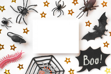 White paper sheet on Halloween background with black bats, spiders and golden stars. Modern Holiday Mock up. Halloween party invitation. Flat lay, top view, copy space. Thanksgiving fall decoration