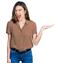 Young caucasian girl presenting with open palms, holding something angry and mad screaming...
