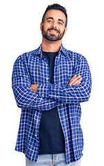 Young hispanic man wearing casual clothes happy face smiling with crossed arms looking at the...
