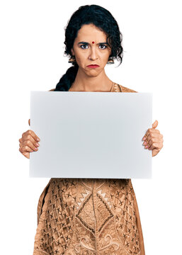 Young indian woman wearing traditional dress holding blank empty banner depressed and worry for distress, crying angry and afraid. sad expression.