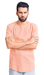 Fototapeta premium Young handsome man with beard wearing casual t-shirt skeptic and nervous, disapproving expression on face with crossed arms. negative person.